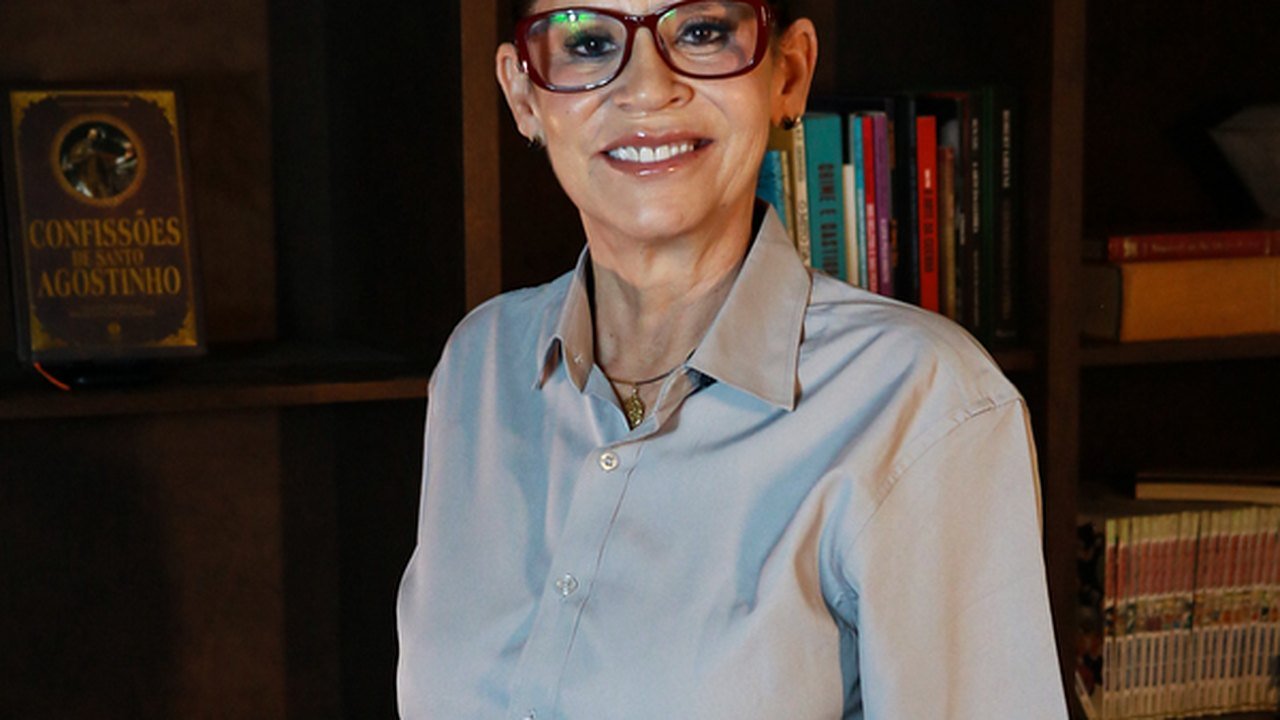 Andréia Braga em ambiente de biblioteca, sorrindo